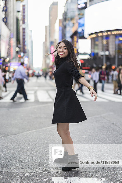 USA  New York City  Manhattan  fröhliche junge Frau im schwarzen Tanz auf der Straße
