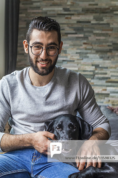 Porträt eines lächelnden jungen Mannes mit seinem Hund zu Hause