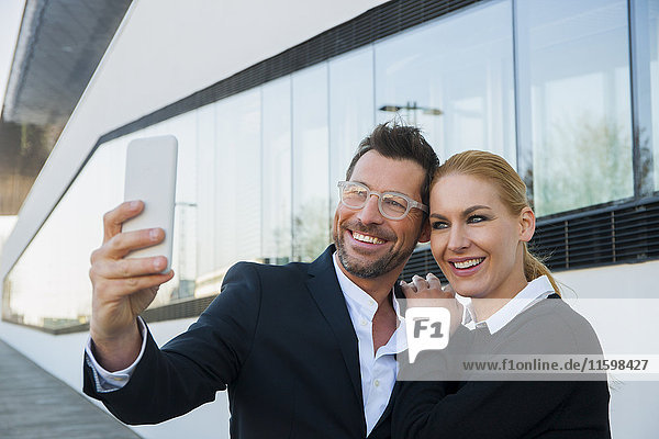 Lächelnder Geschäftsmann mit einer Frau  die einen Selfie nimmt.