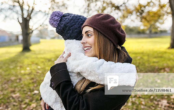 Happy mother embracing her little daughter in autumnal park