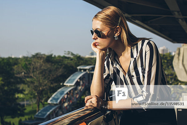 Stilvolle junge Frau genießt das Sonnenlicht auf der Terrasse