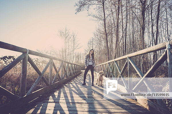 Frau steht mit ihrem Hund auf der Brücke