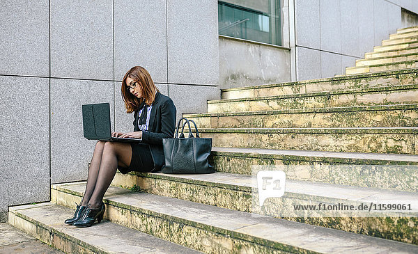 Geschäftsfrau auf der Treppe sitzend  mit Laptop