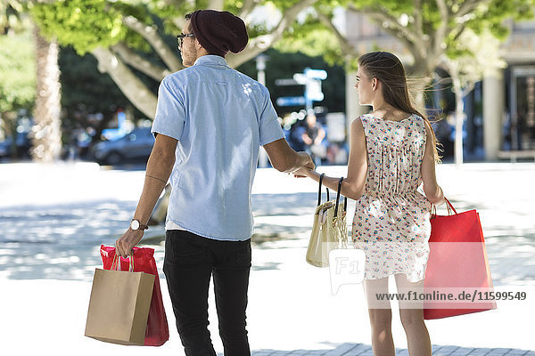 Junges Paar mit Einkaufstüten zu Fuß in der Stadt