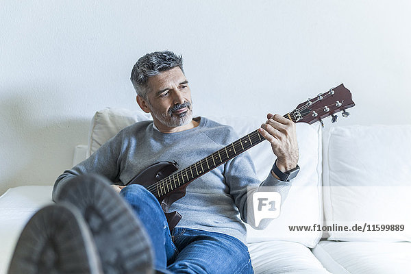 Mature man at home playing electric guitar