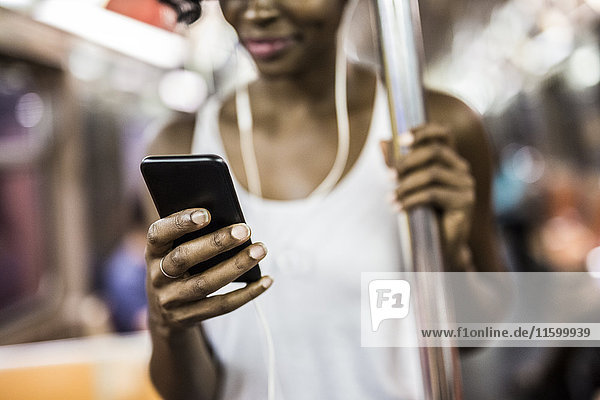 Woman's hand holding cell phone in underground train