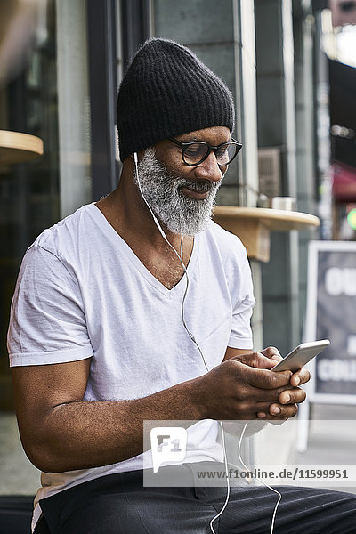 Mature man using smartphone in coffee shop