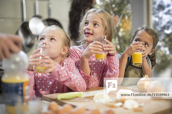 Girls drinking juice in kitchen looking up