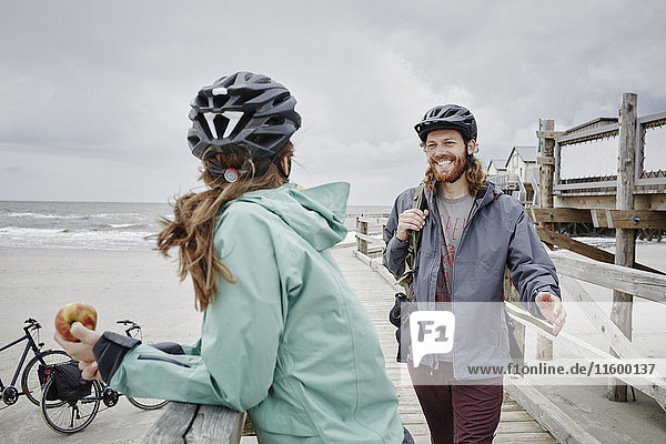 Germany  Schleswig-Holstein  St Peter-Ording  couple on a bicycle trip having a break on jetty at the beach