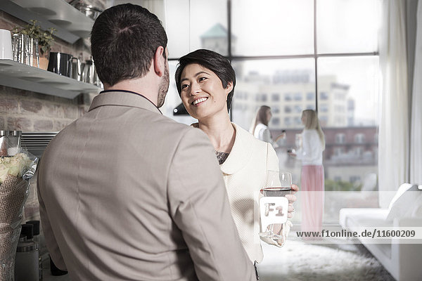Man and woman with red wine glass socializing in a city apartment