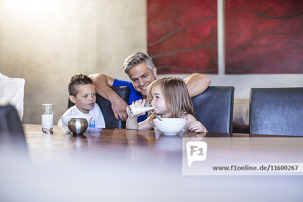 Happy father with children seated having breakfast at table
