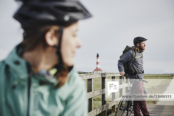 Germany  Schleswig-Holstein  Eiderstedt  couple on bicycle trip having a break near Westerheversand Lighthouse
