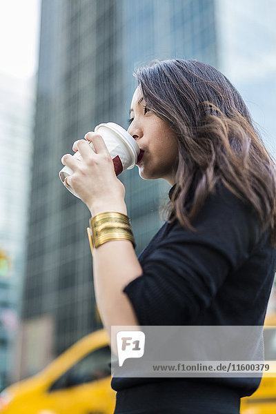 USA  New York City  Manhattan  junge Frau  die Kaffee trinkt  um auf die Straße zu gehen.