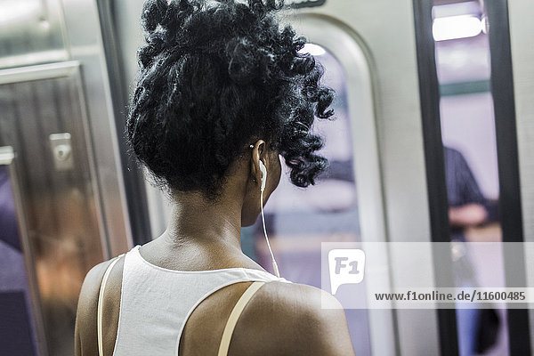 Back view of woman with earphones in underground train