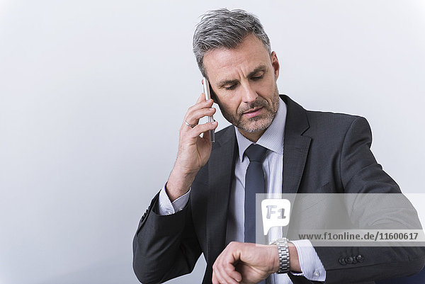 Businessman talking on the phone and checking the time
