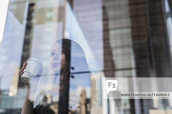 USA  New York City  Manhattan  junge Frau mit Kaffee hinter Glasscheibe