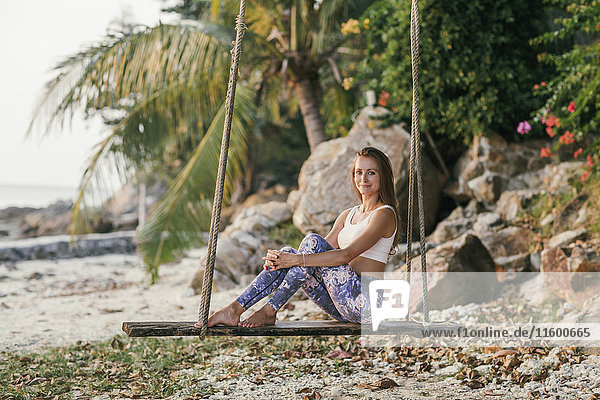 Frau auf einer Schaukel am Strand sitzend