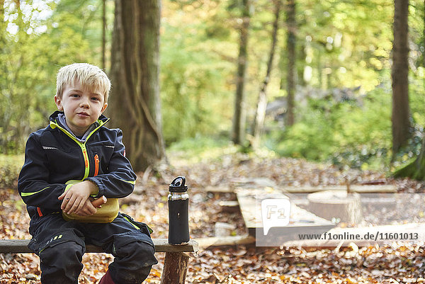 Porträt eines blonden kleinen Jungen beim Mittagessen im Wald
