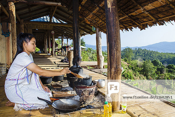 Asiatische Frau kocht auf der Terrasse im Freien