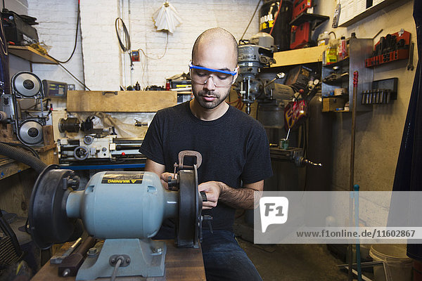 Mann mit gemischter Rasse benutzt Maschinen in einer Werkstatt
