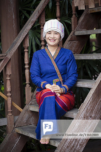 Asian woman wearing traditional clothing sitting on staircase