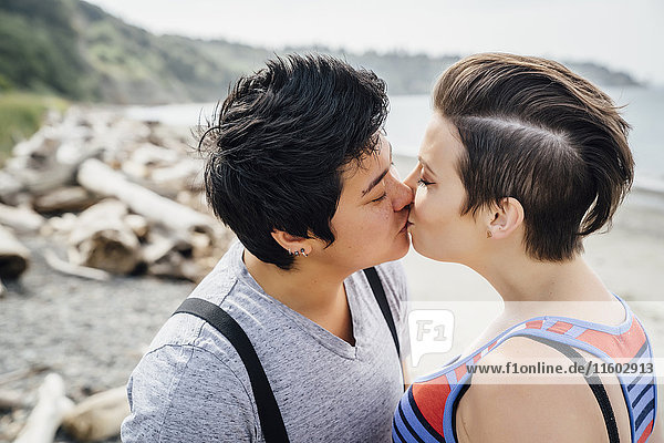 Schwangeres lesbisches Paar küsst sich am Strand