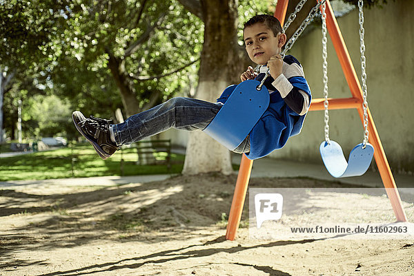 Hispanic boy on swing at park