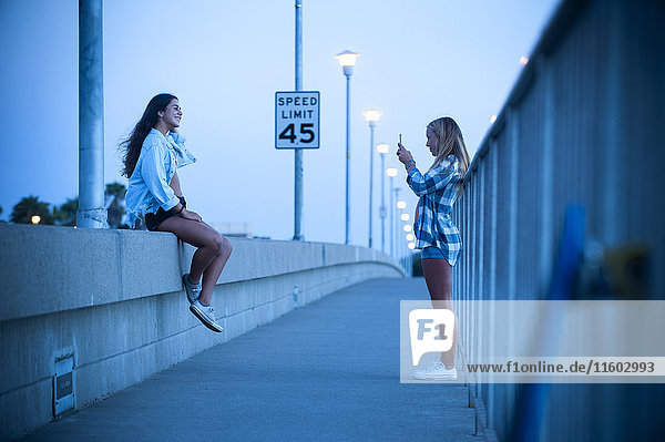 Teenager-Mädchen fotografiert Freund an der Wand sitzend