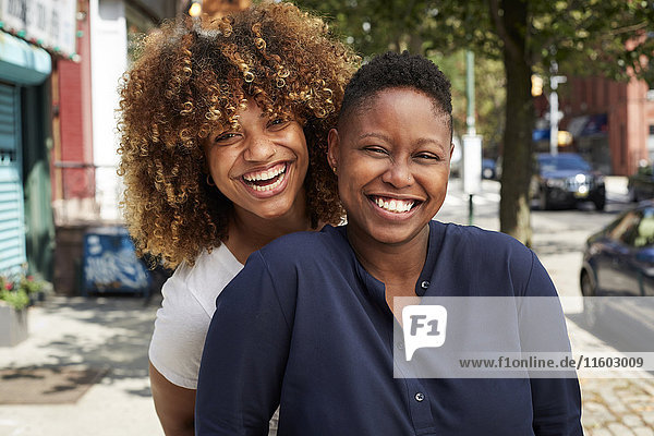 Black women smiling on city sidewalk