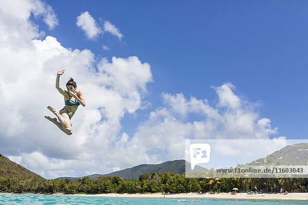 Caucasian woman jumping into tropical ocean