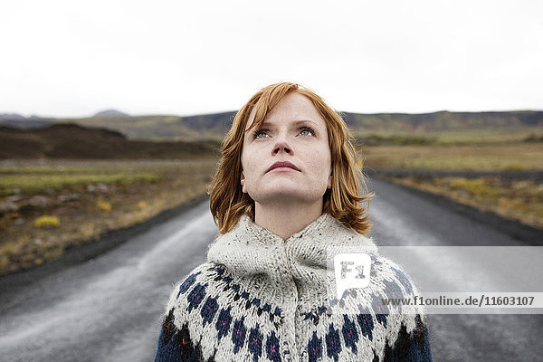 Caucasian woman wearing sweater in road looking up