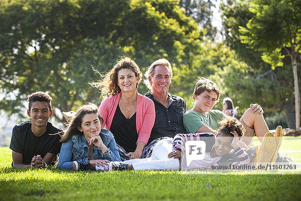 Porträt einer lächelnden Familie im Gras eines Parks