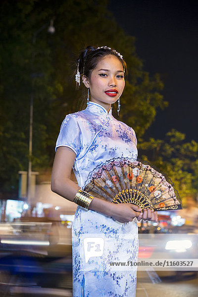Porträt einer asiatischen Frau in traditioneller Kleidung mit Fächer