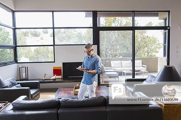 Caucasian man standing in livingroom using digital tablet