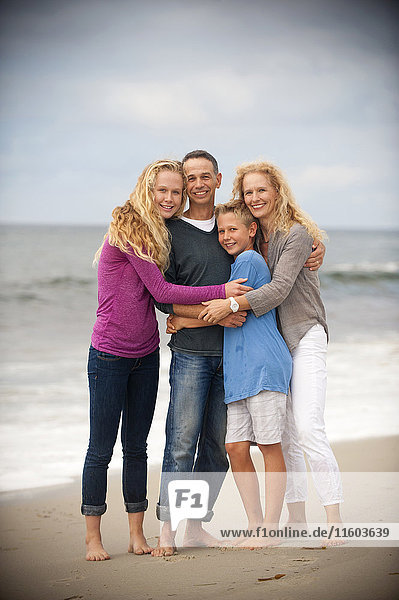 Porträt einer lächelnden Familie  die sich am Strand umarmt