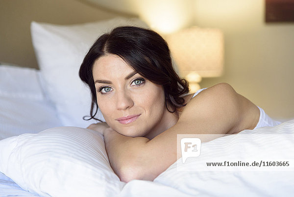 Lächelnde kaukasische Frau auf dem Bett liegend