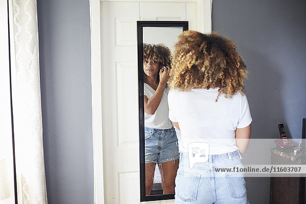 Schwarze Frau begutachtet Haare im Spiegel