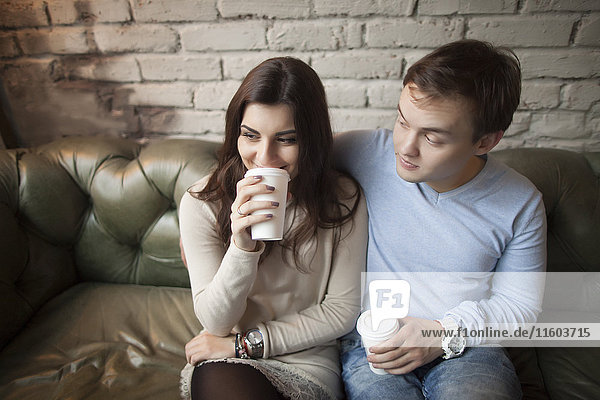 Caucasian couple drinking coffee on sofa
