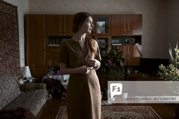 Pensive Caucasian woman standing in livingroom