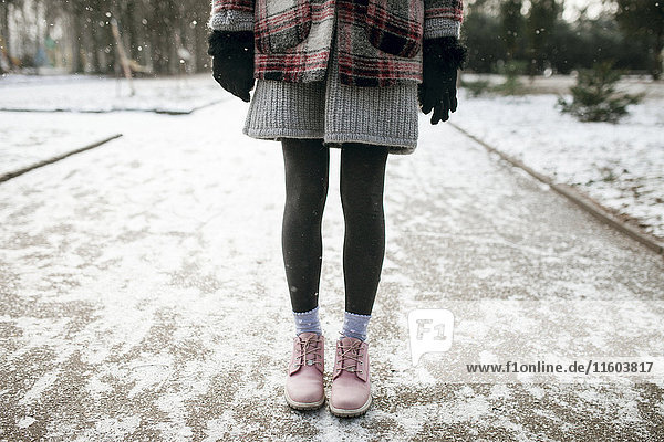 Beine einer im Schnee stehenden kaukasischen Frau