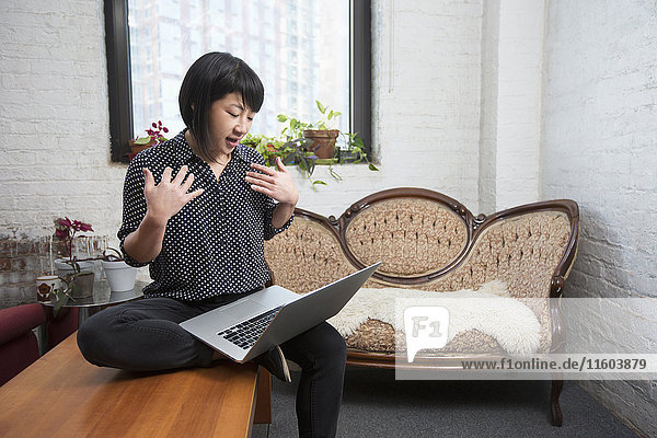 Asian woman video chatting on laptop