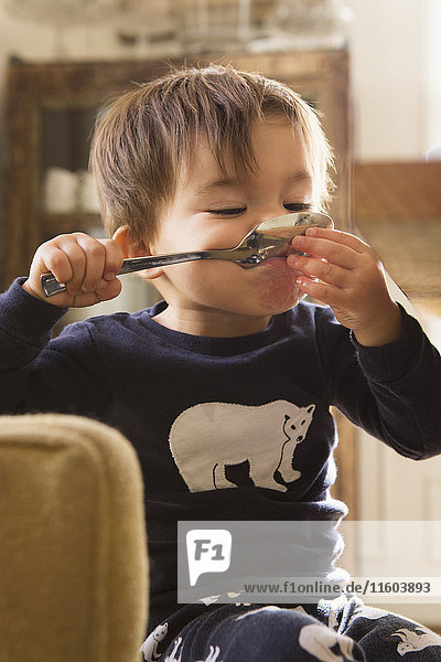 Mixed Race boy holding spoon in mouth