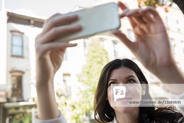 Lächelnde kaukasische Frau  die für ein Selfie mit ihrem Handy posiert