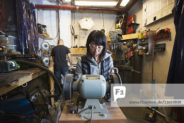 Mann und Frau benutzen Maschinen in einer Werkstatt