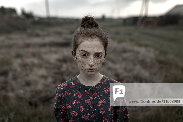 Caucasian girl with freckles raising eyebrow in field