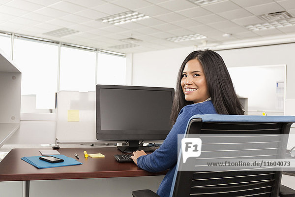 Smiling Pacific Islander woman using computer in office
