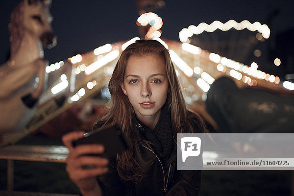 Kaukasisches Teenager-Mädchen hält Handy im Vergnügungspark