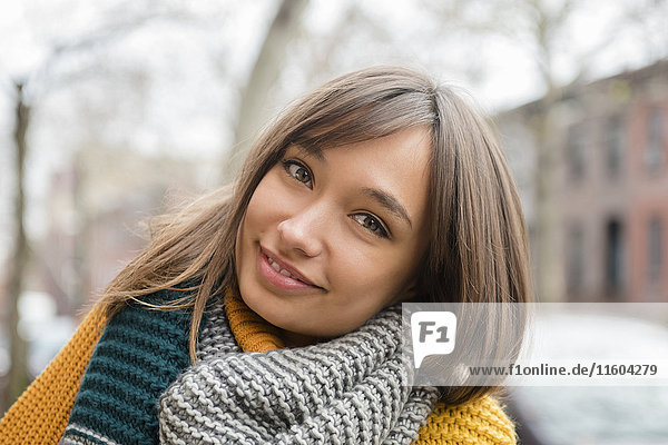 Portrait of smiling Mixed Race woman wearing scarf in city