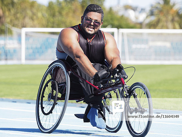Middle Eastern man racing in wheelchair on track
