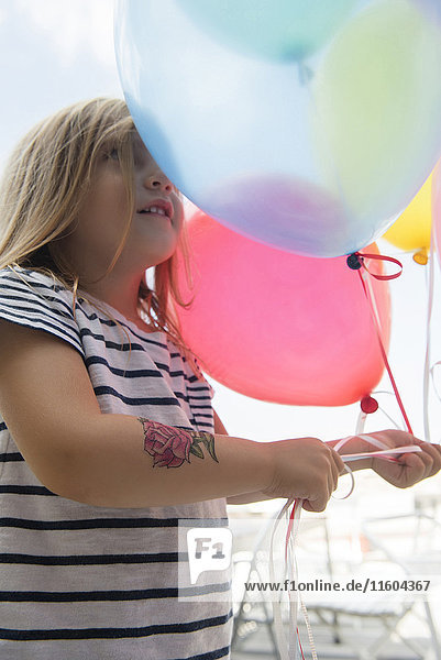 Caucasian girl holding multicolor balloons